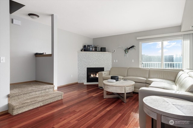 living room featuring a tile fireplace and dark hardwood / wood-style flooring