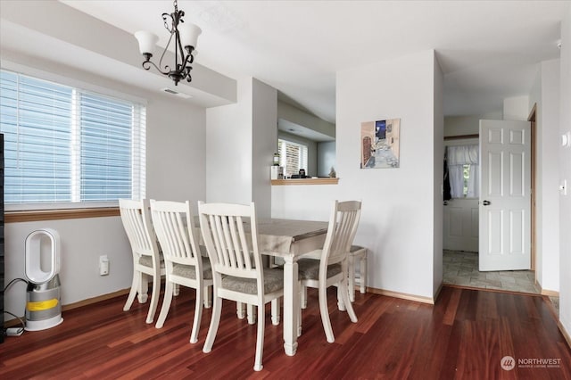 dining space featuring an inviting chandelier, a healthy amount of sunlight, and dark hardwood / wood-style floors