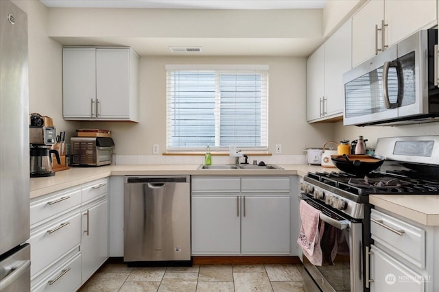 kitchen with appliances with stainless steel finishes, white cabinets, and sink