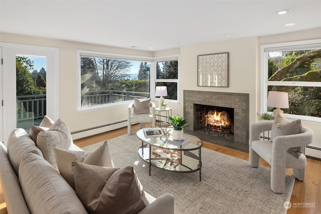 interior space featuring a fireplace, a baseboard radiator, and light wood-type flooring