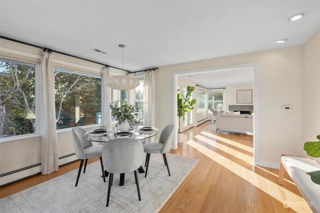 dining area featuring a baseboard radiator and light hardwood / wood-style flooring