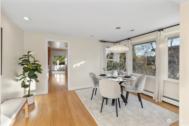 dining room with a baseboard radiator and light hardwood / wood-style flooring