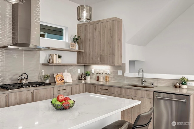 kitchen featuring wall chimney exhaust hood, a kitchen bar, sink, appliances with stainless steel finishes, and pendant lighting