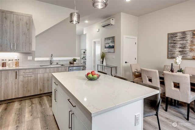 kitchen featuring a kitchen island, a wall mounted air conditioner, sink, hanging light fixtures, and light hardwood / wood-style flooring