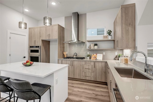 kitchen with wall chimney exhaust hood, stainless steel appliances, sink, and a breakfast bar area