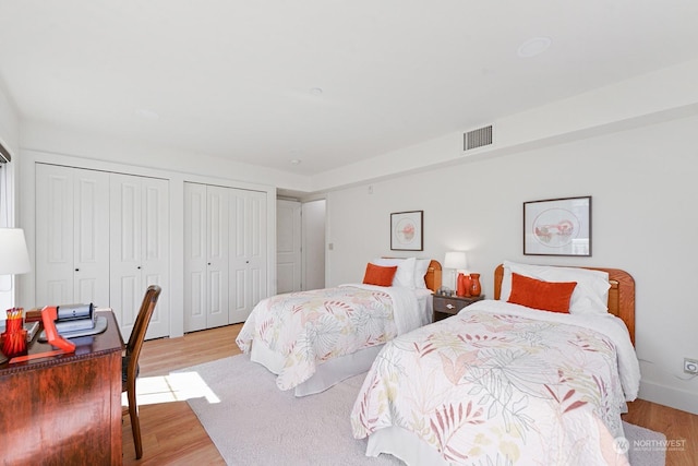 bedroom featuring two closets and light hardwood / wood-style flooring