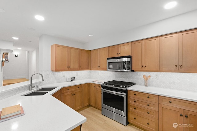 kitchen featuring stainless steel appliances, tasteful backsplash, sink, and light wood-type flooring