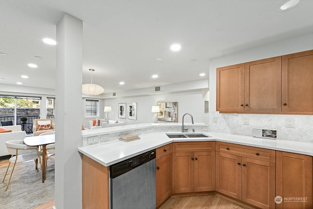 kitchen featuring sink, tasteful backsplash, stainless steel dishwasher, kitchen peninsula, and light wood-type flooring