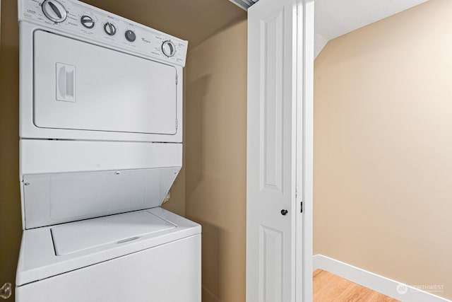 laundry room featuring light hardwood / wood-style floors and stacked washer / dryer