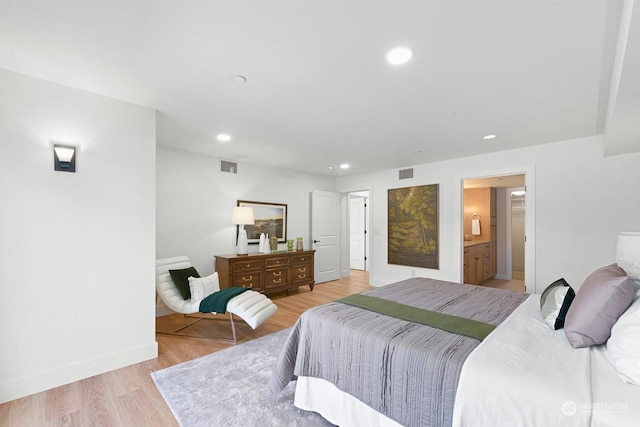 bedroom with light wood-type flooring and ensuite bathroom