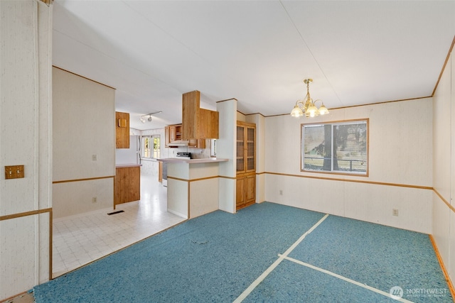 kitchen featuring decorative light fixtures, wood walls, an inviting chandelier, and kitchen peninsula