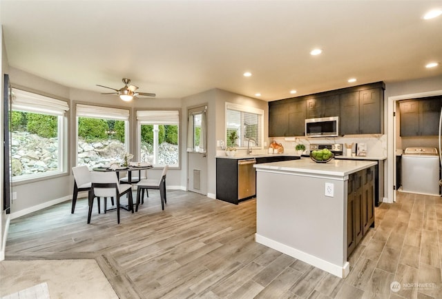 kitchen featuring stainless steel appliances, a kitchen island, ceiling fan, and light hardwood / wood-style flooring