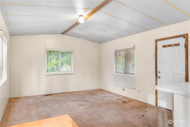 empty room featuring light colored carpet, vaulted ceiling, and a healthy amount of sunlight