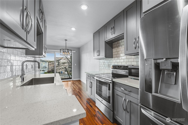 kitchen with dark hardwood / wood-style flooring, sink, appliances with stainless steel finishes, light stone counters, and decorative backsplash