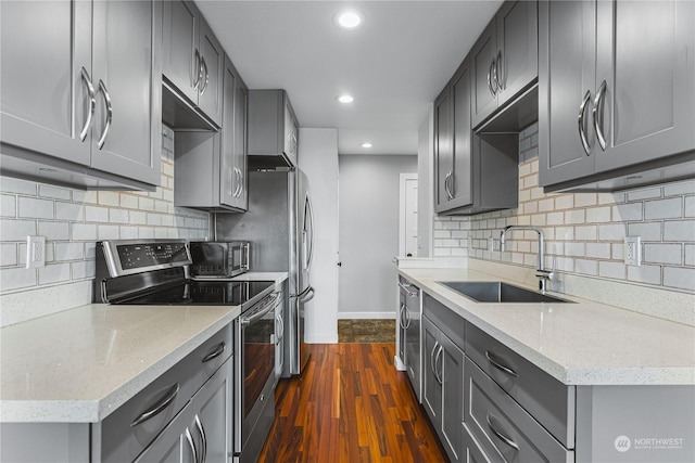 kitchen featuring sink, dark wood-type flooring, stainless steel appliances, light stone counters, and gray cabinets