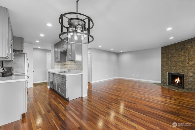 kitchen with sink, a stone fireplace, decorative backsplash, and gray cabinets