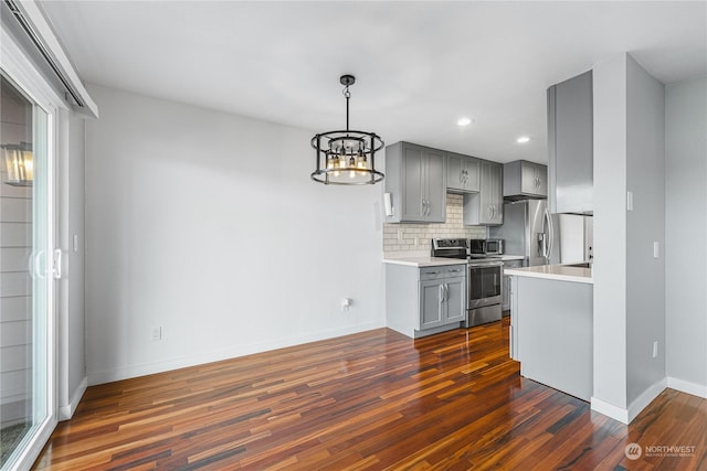 kitchen featuring dark hardwood / wood-style flooring, tasteful backsplash, gray cabinets, a notable chandelier, and stainless steel appliances