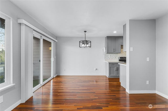 unfurnished dining area with a notable chandelier and dark hardwood / wood-style floors