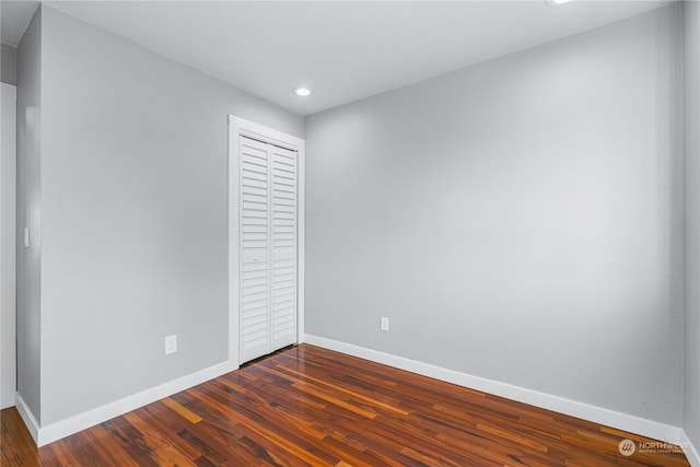 unfurnished bedroom with a closet and dark wood-type flooring