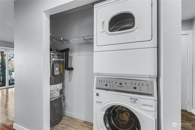 laundry area with tile patterned floors, water heater, and stacked washer and dryer