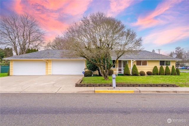 ranch-style home featuring a garage and a lawn