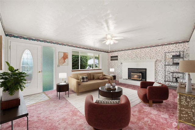 living room featuring ceiling fan, crown molding, and a fireplace