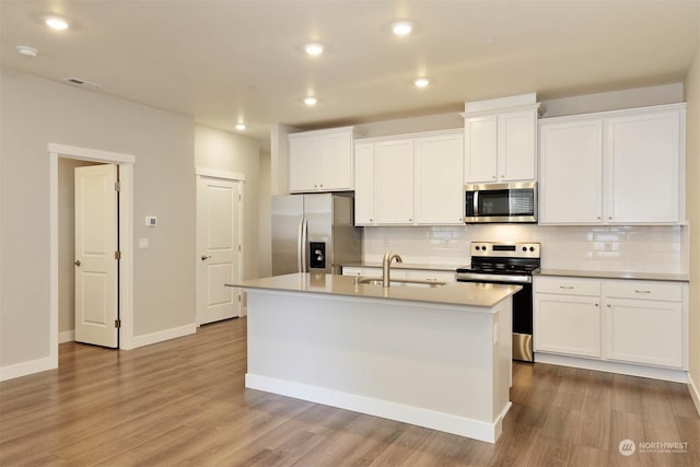 kitchen with sink, stainless steel appliances, white cabinets, a center island with sink, and decorative backsplash