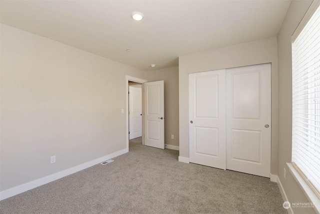 unfurnished bedroom featuring light carpet and a closet