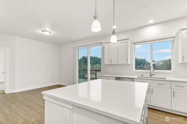 kitchen featuring pendant lighting, tasteful backsplash, sink, white cabinets, and light hardwood / wood-style floors