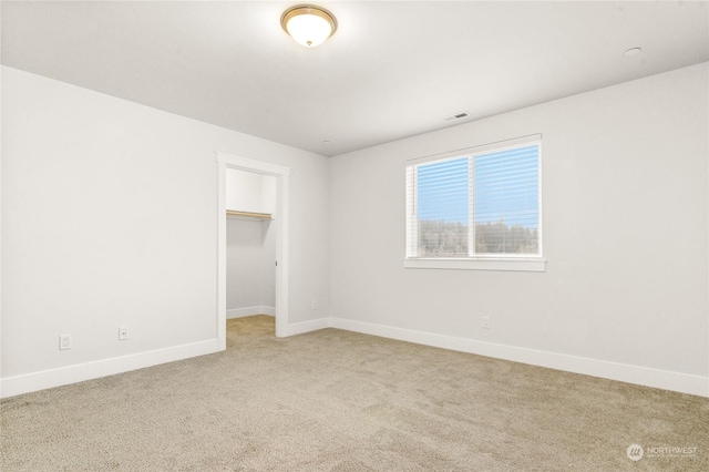 unfurnished bedroom featuring a closet, a spacious closet, and light carpet