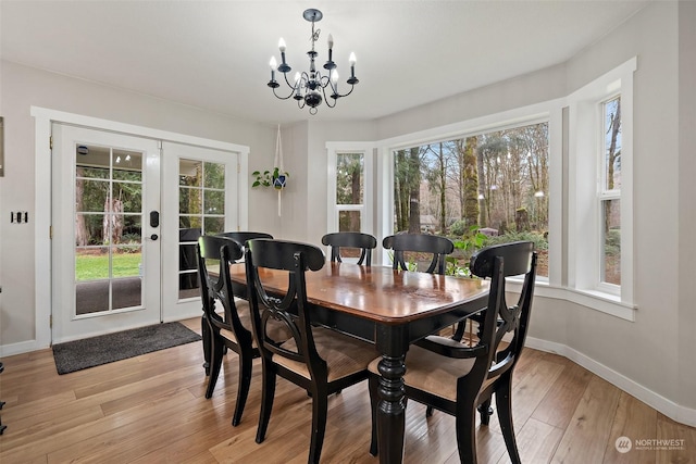 dining space with a notable chandelier, light hardwood / wood-style flooring, and french doors