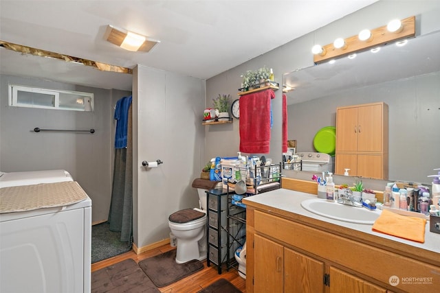 bathroom with washer / dryer, wood-type flooring, vanity, and toilet