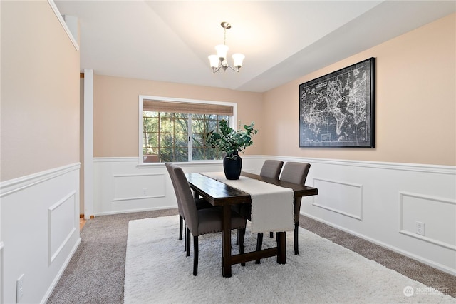 dining room with an inviting chandelier, lofted ceiling, and carpet floors