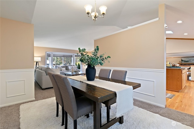 dining area with vaulted ceiling, light colored carpet, and an inviting chandelier