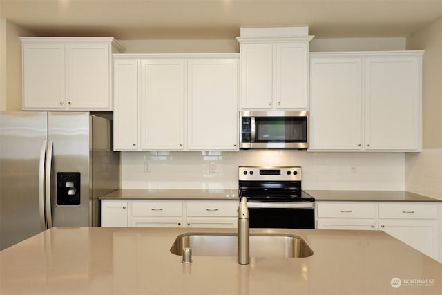 kitchen with tasteful backsplash, white cabinetry, appliances with stainless steel finishes, and sink