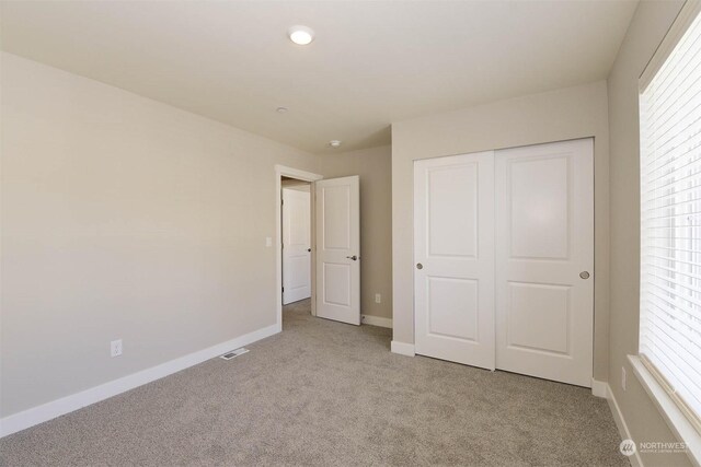 unfurnished bedroom featuring light carpet and a closet