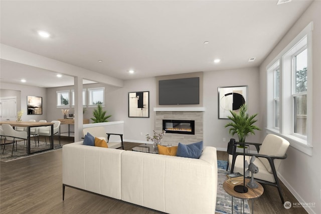 living room with dark wood-type flooring, a tiled fireplace, and plenty of natural light