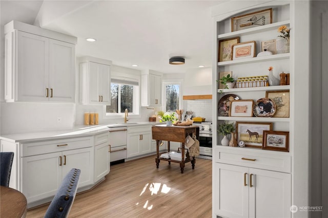 kitchen featuring dishwasher, white cabinetry, sink, backsplash, and light hardwood / wood-style floors