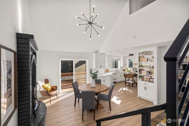 dining room with high vaulted ceiling, sink, an inviting chandelier, and light hardwood / wood-style floors