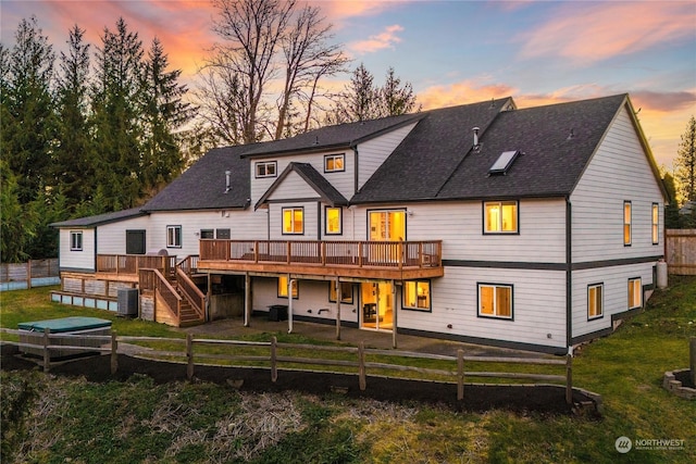 back house at dusk with central AC and a deck