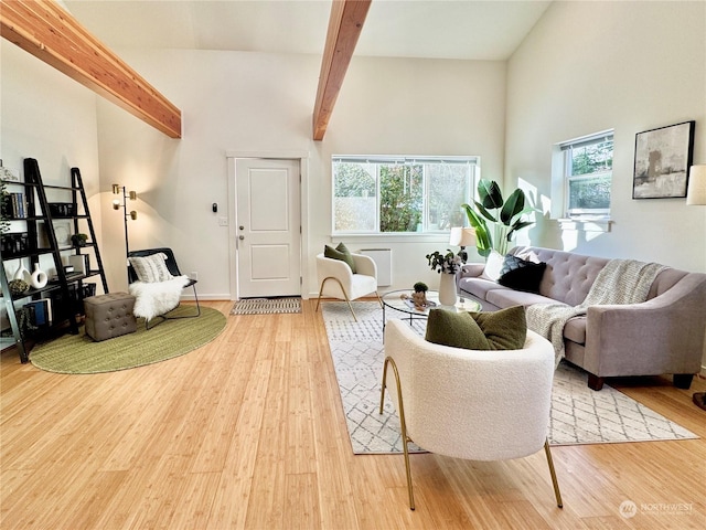 living room with hardwood / wood-style flooring, a towering ceiling, and beamed ceiling