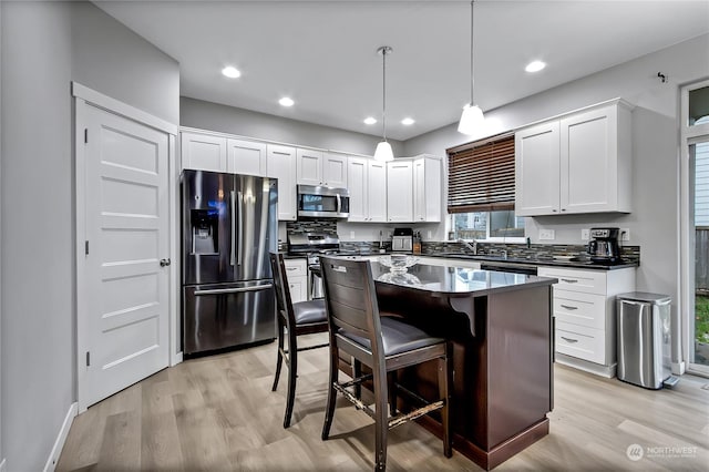 kitchen featuring a kitchen breakfast bar, hanging light fixtures, a kitchen island, white cabinetry, and stainless steel appliances