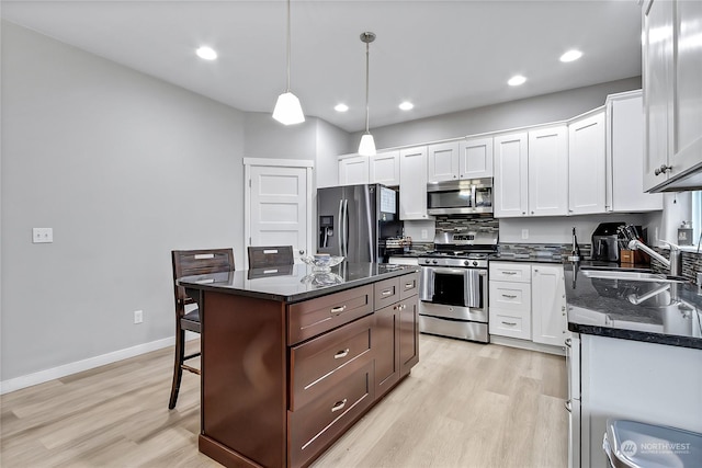 kitchen featuring a center island, white cabinets, sink, hanging light fixtures, and stainless steel appliances