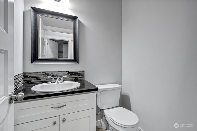 bathroom featuring vanity, toilet, and backsplash