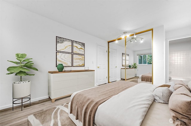 bedroom with ensuite bath and light hardwood / wood-style floors