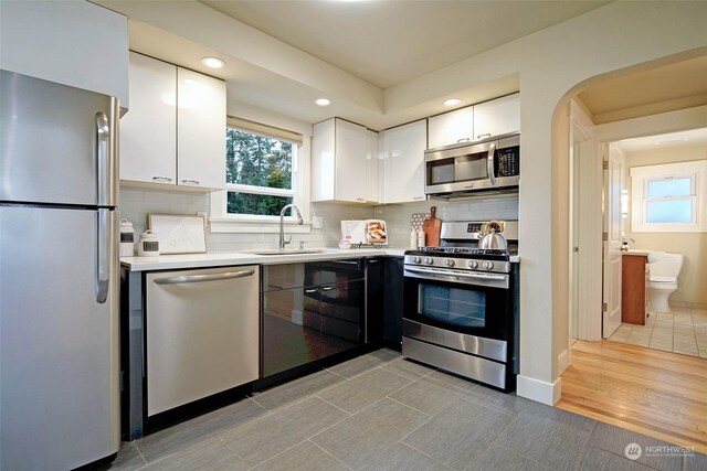 kitchen featuring appliances with stainless steel finishes, decorative backsplash, white cabinetry, and sink