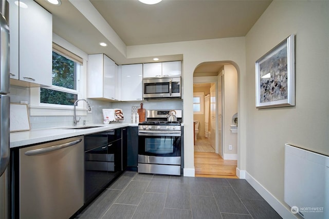 kitchen with white cabinetry, stainless steel appliances, backsplash, and sink