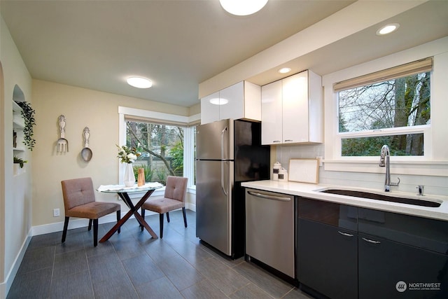 kitchen with white cabinetry, appliances with stainless steel finishes, decorative backsplash, a wealth of natural light, and sink