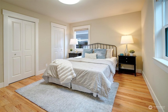 bedroom with wood-type flooring, multiple windows, and two closets