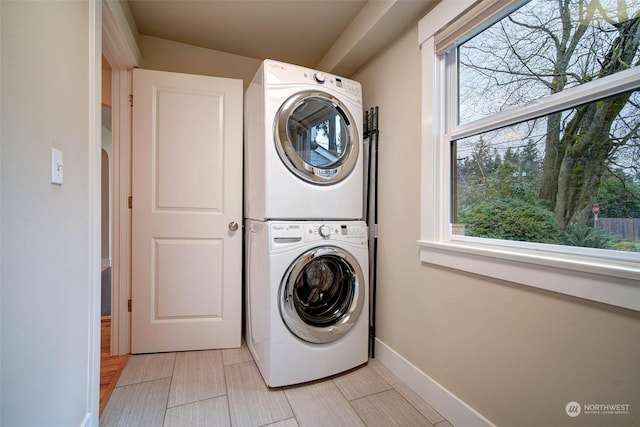 laundry area with stacked washing maching and dryer and a healthy amount of sunlight